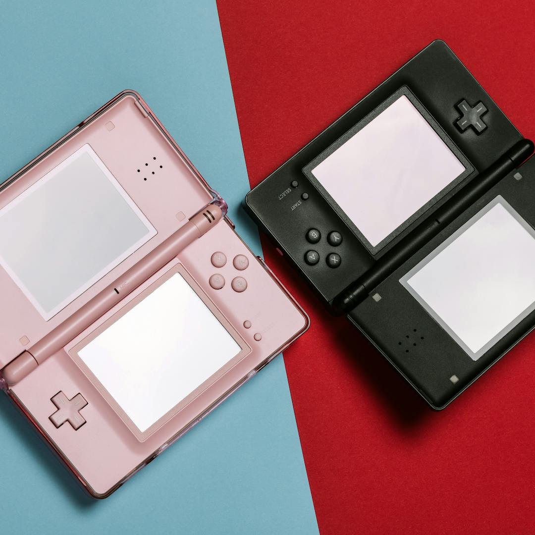 pink and black Nintendo DS consoles on contrasting backgrounds
