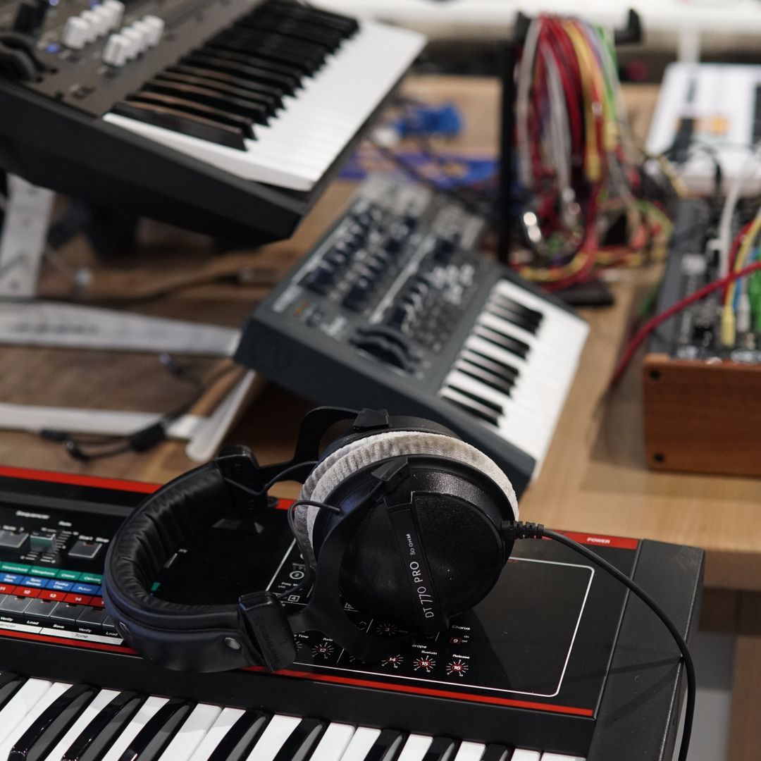 cluttered music studio with synthesizers and headphones