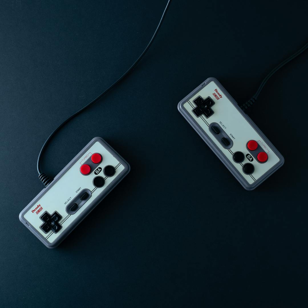 two retro gaming controllers on dark background